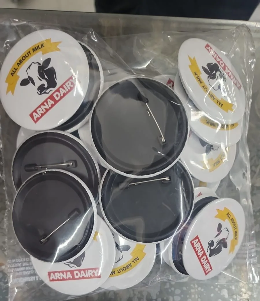 Round Arna Dairy pin badges printed with the All About Milk logo, packed in bulk