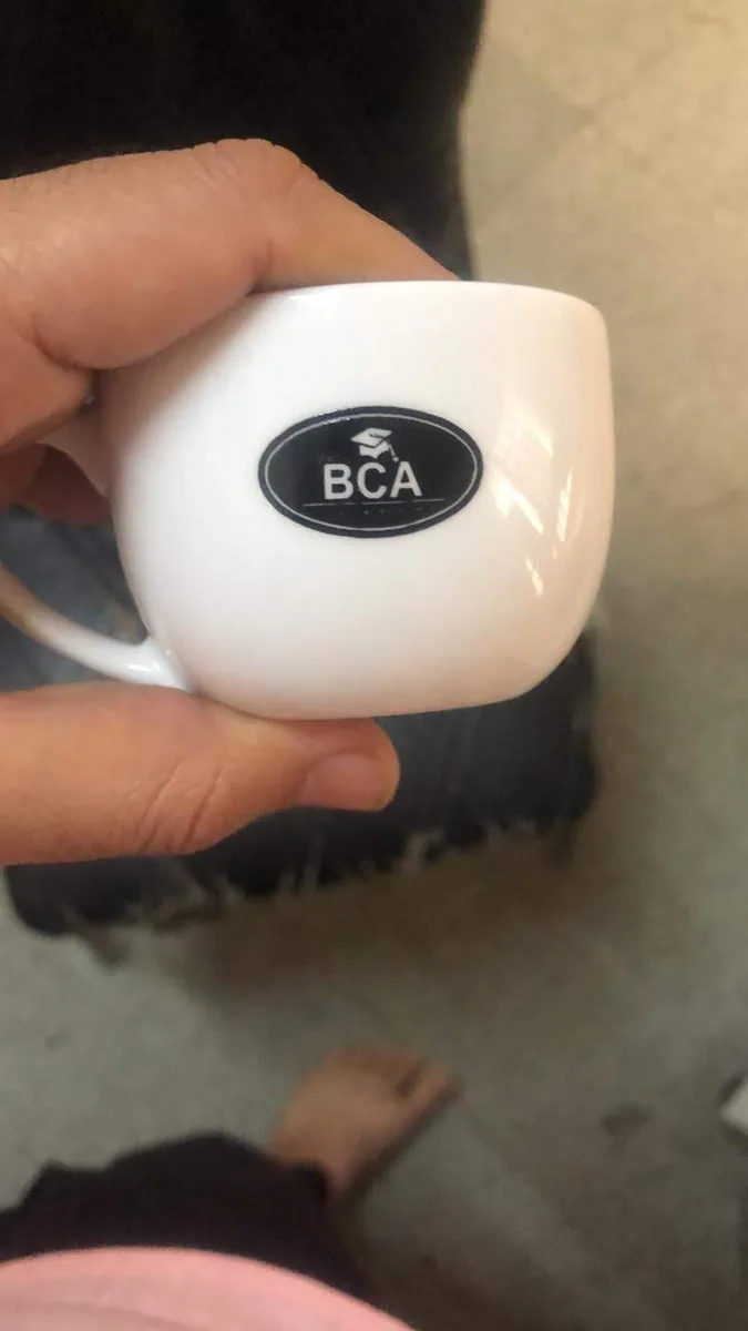 White ceramic tea cup branded with the black oval BCA logo