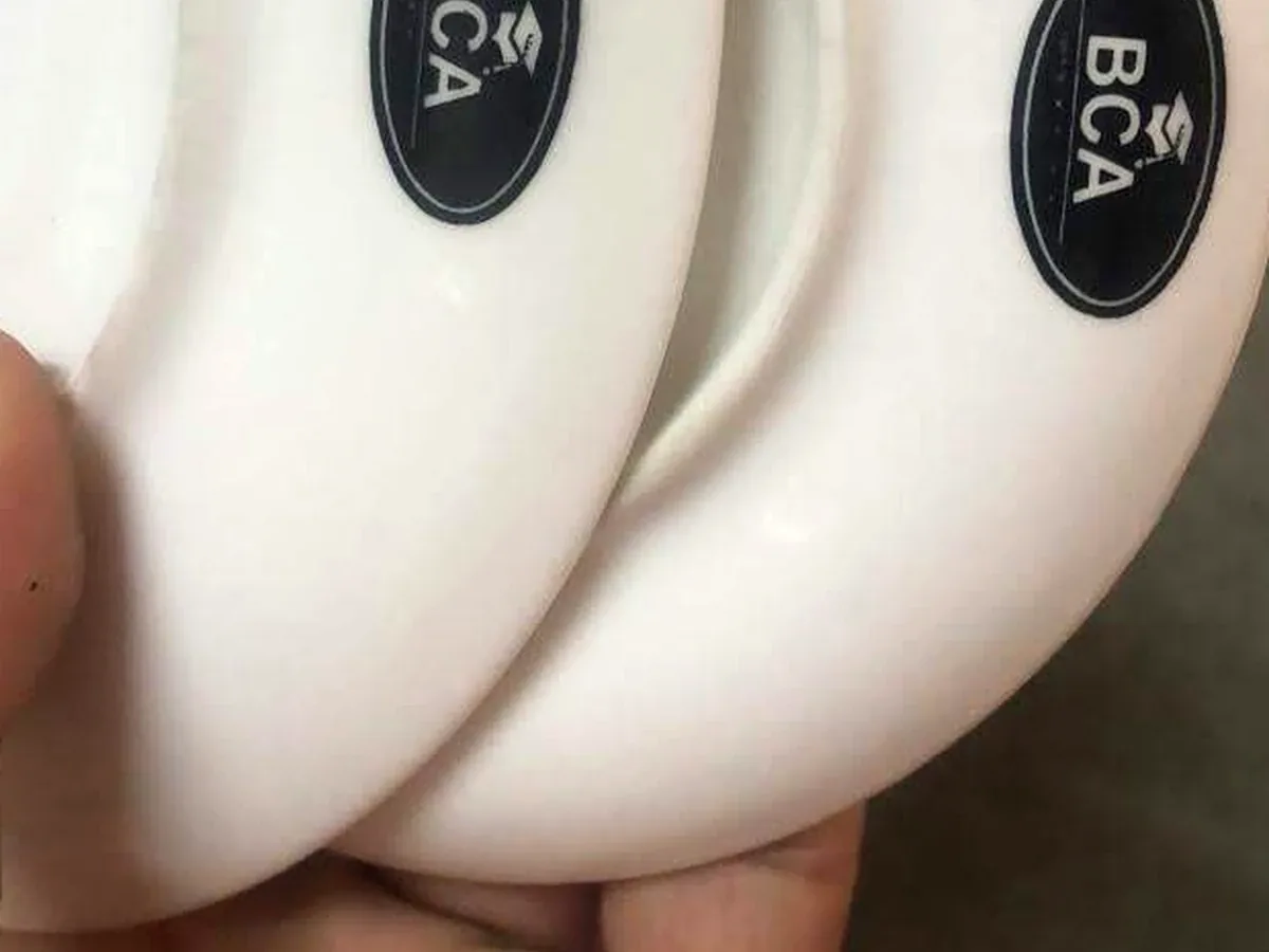 Stack of white ceramic BCA branded saucers held in hand