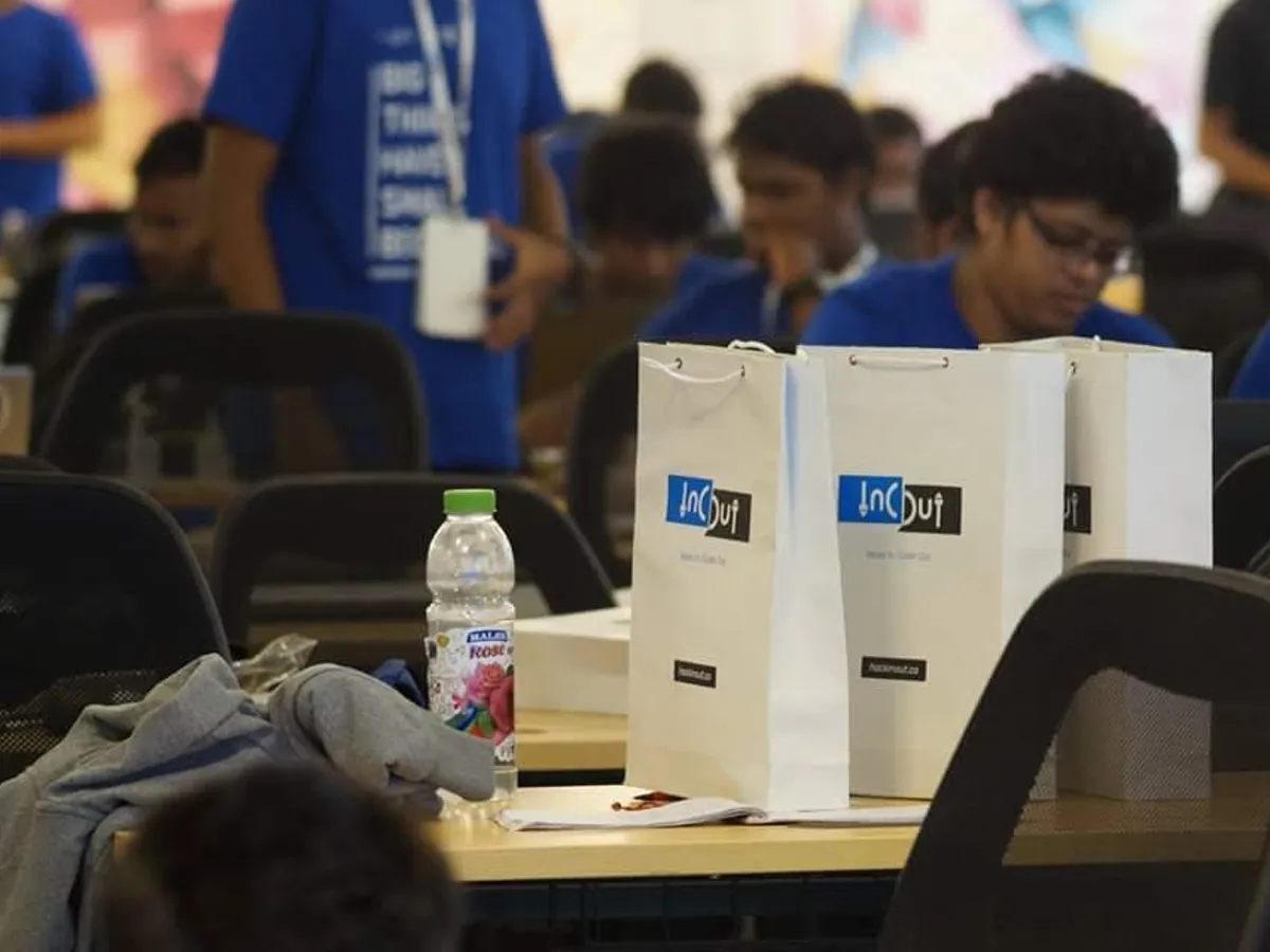 Devfolio branded paper bags on desks at a hackathon venue