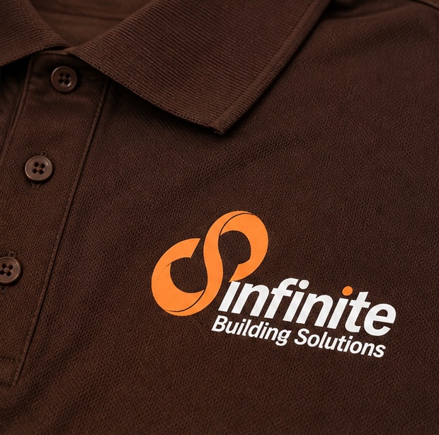 Close-up of the orange and white Infinite Building Solutions logo screen printed on brown polo fabric