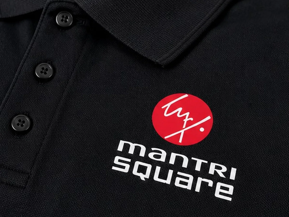 Close-up of the screen printed Mantri Square logo on the black polo T-shirt