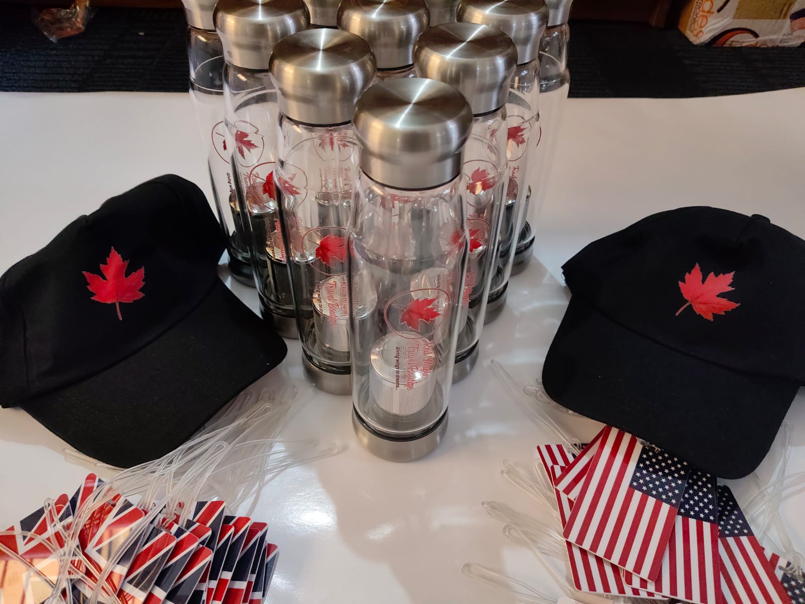 Two black caps with red maple leaf branding beside the branded bottles