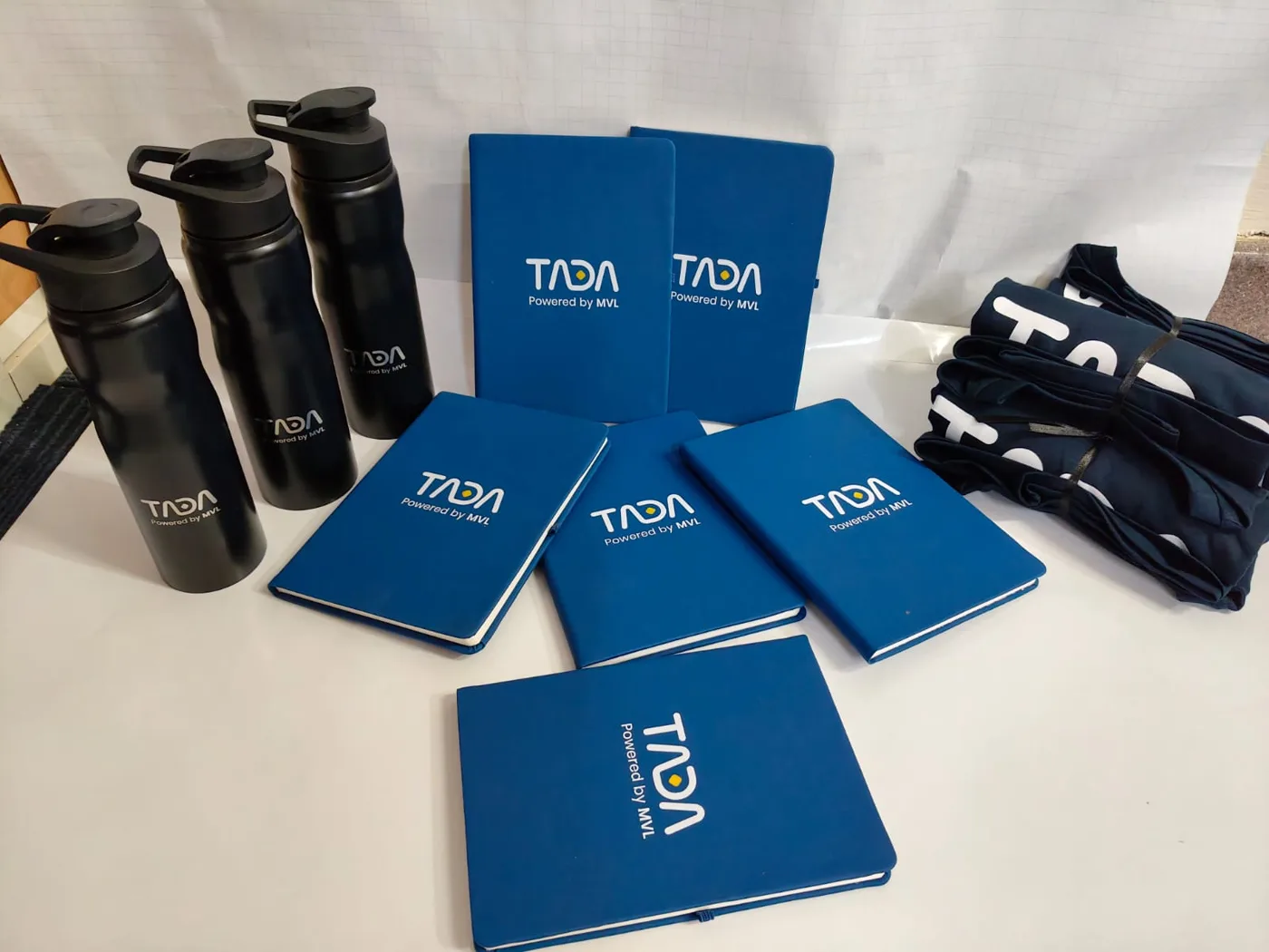 TADA engraved black bottles, blue printed diaries and folded printed T-shirts