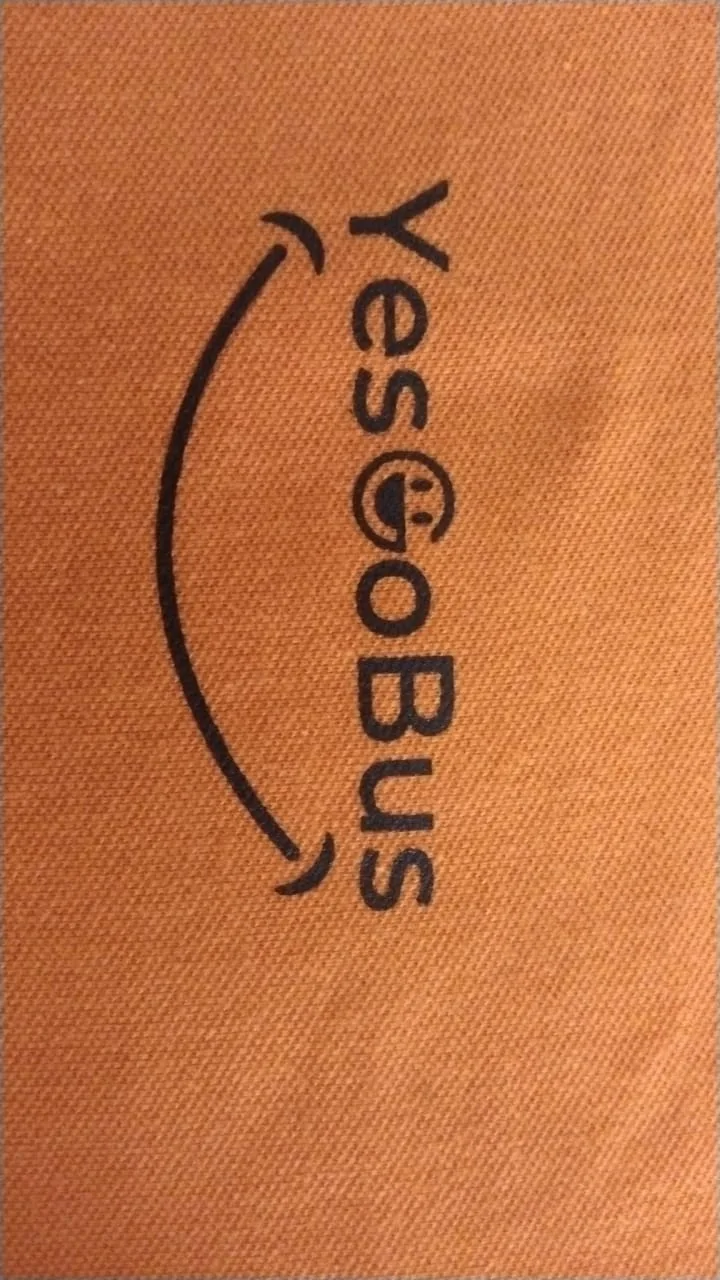 Close-up of the Yes Go Bus logo screen printed on orange fabric