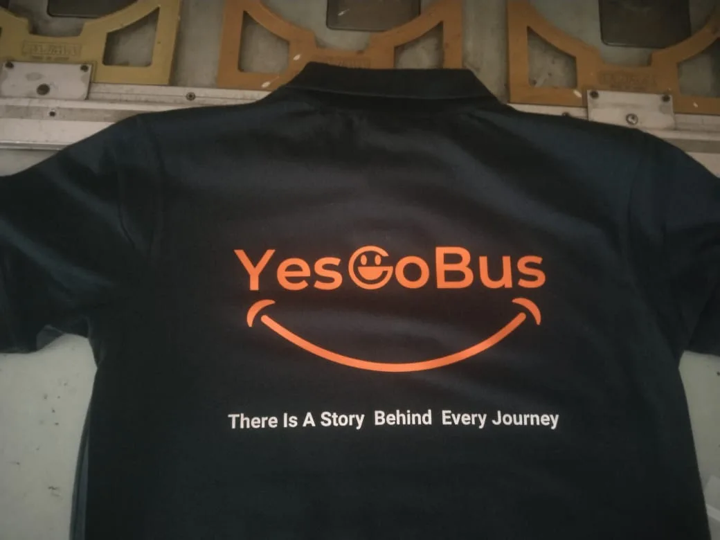 Back of the black Yes Go Bus polo with the large orange screen printed logo and tagline